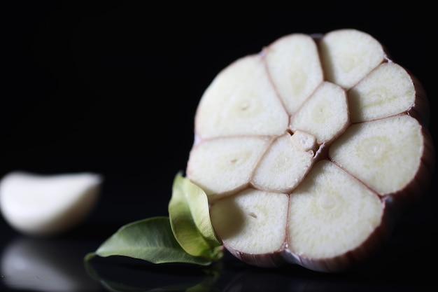 Fresh garlic clove on black background. Garlic is rich in vitamins, useful spring, good spices. Garlic sliced on a dark background. Raw sliced garlic.