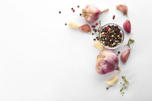 Fresh garlic and pepper grains on white background top view