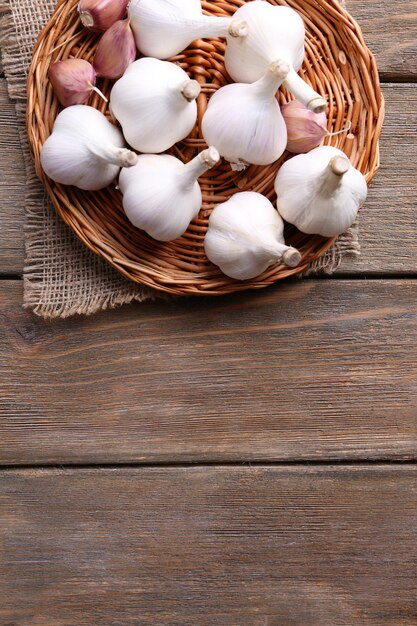 Fresh garlic on wicker mat on wooden background