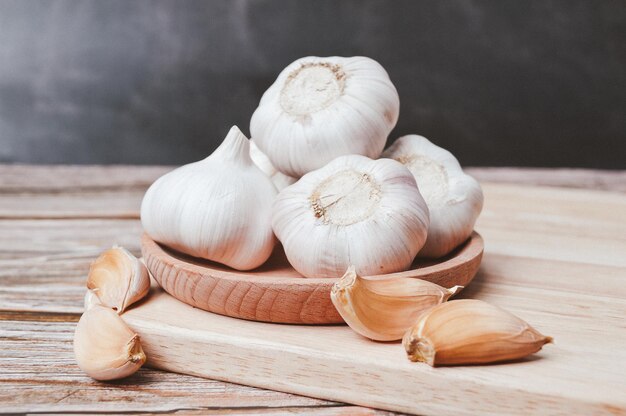 Fresh garlic on wooden plate Garlic is a species in the onion genus Allium Selective focus