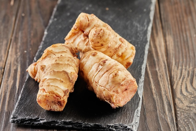 Fresh ginger on black stone on wooden background