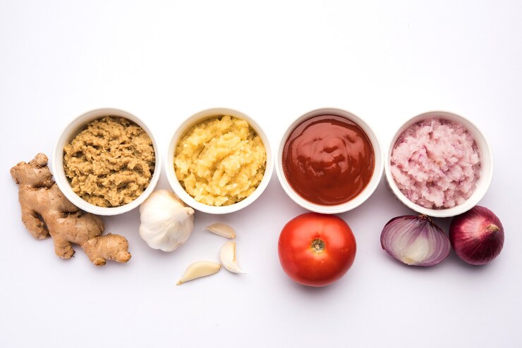 Photo fresh ginger, garlic, onion and tomato puree also known as adrak, lahsun, pyaj and tamatar paste in hindi. basic indian food ingredients in a bowl over moody background
