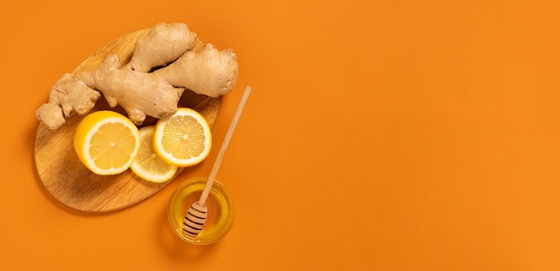 Fresh ginger root lemon honey orange background Alternative medicine vegetarianism
