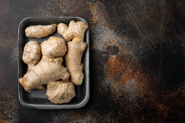 Fresh ginger root set, in plastic market  container, on old dark rustic table, top view flat lay