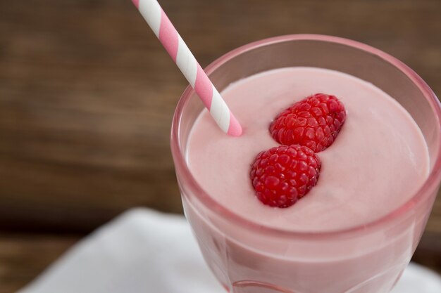 Fresh glass of smoothie with straw on wooden table