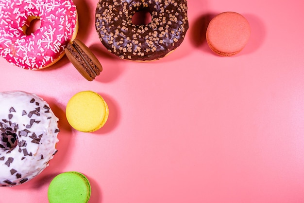 Fresh glazed donuts and french macaroons isolated on a pink background