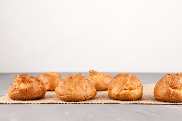 Panini dorati freschi dalla pasta alla crema (profiteroles) su un tavolo luminoso