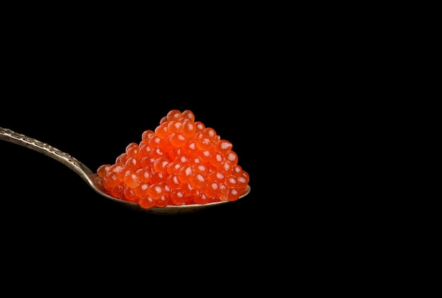 Photo fresh grainy red chum salmon caviar in a metal spoon, delicious and healthy food, copy space