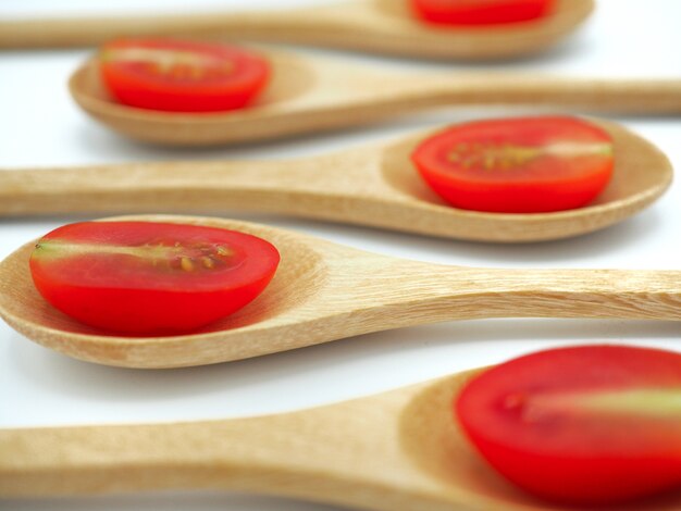 Fresh grape or cherry tomato with wooden spoon on white background.