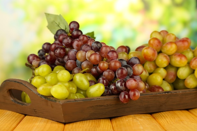 Fresh grape on wooden tray on bright background