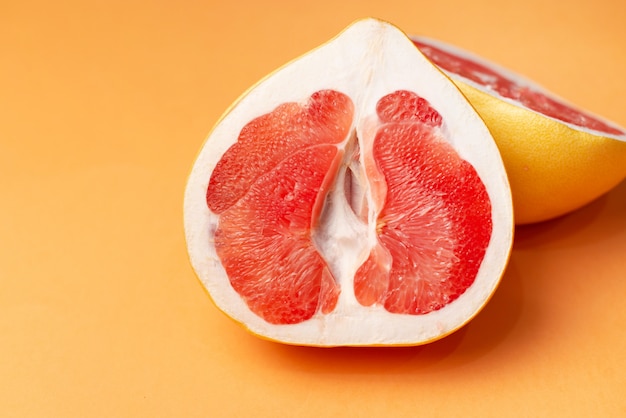 Fresh grapefruit on an orange surface, close-up. Sex concept. The concept of women's health.