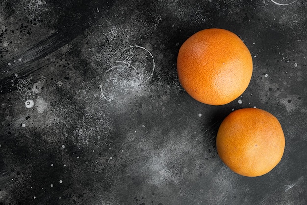 Fresh grapefruits set, on black dark stone table background, top view flat lay, with copy space for text