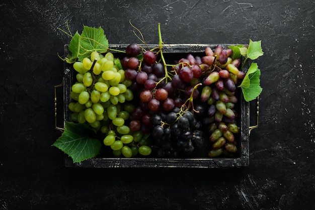 Fresh grapes with leaves on a black stone table Top view Free space for your text