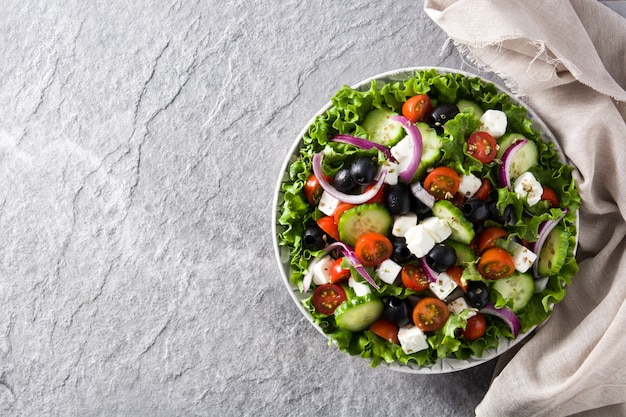 Fresh Greek salad in Plate with black olive,tomato,feta cheese, cucumber and onion on gray Copyspace