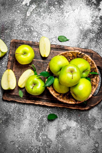 Fresh green apples on cutting Board on rustic table.