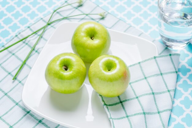 Fresh green apples in a dish on table.