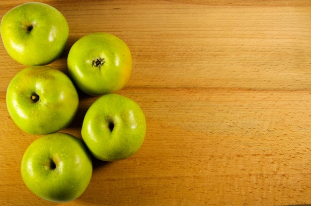 Fresh green apples on the wooden background