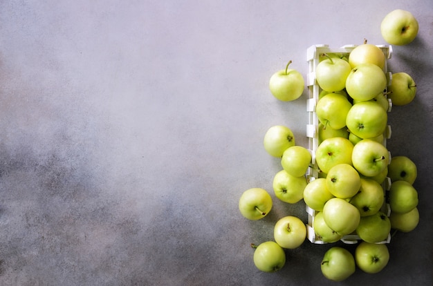 Fresh green apples in wooden box on light grey . 