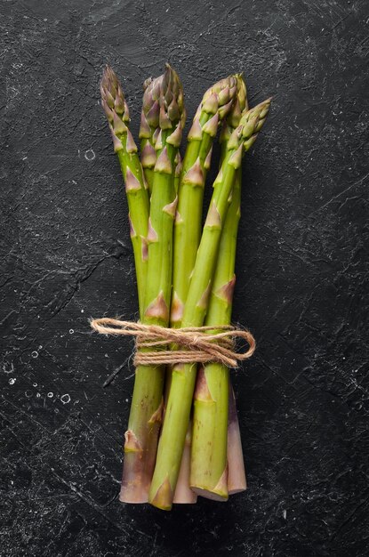 Fresh green asparagus on a black stone background. Healthy food. Top view, free copy space.