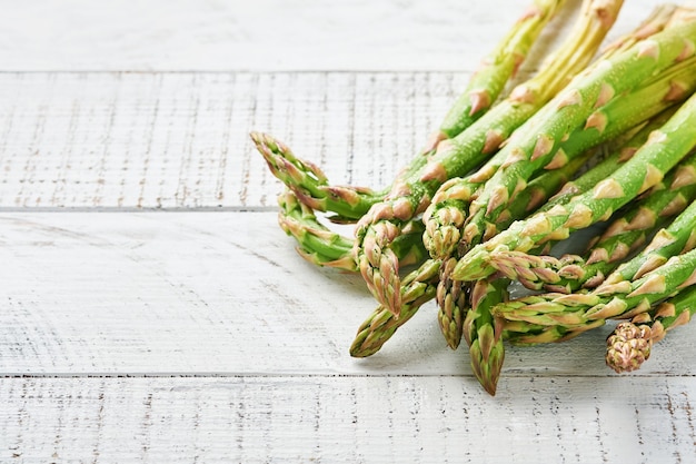 Fresh green asparagus bunch ready for cooking on white old wooden background