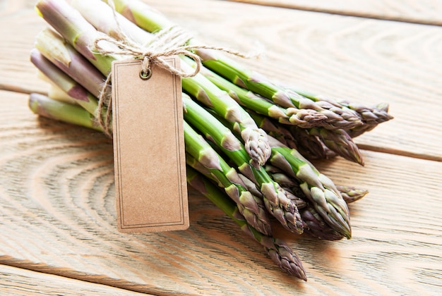 Fresh green asparagus with empty tag on old wooden table.