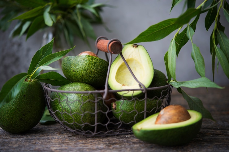 Photo fresh green avocado with leaves on wooden space