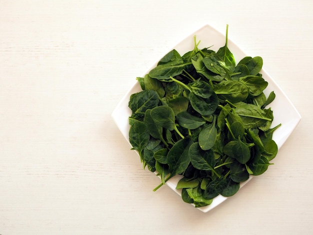 Photo fresh green baby spinach in a bowl on white top view