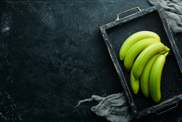 Fresh green bananas on black stone background Top view Free space for your text