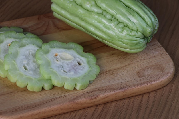 Fresh green bitter cucumbers or chinese bitter,slices on wooden plate.