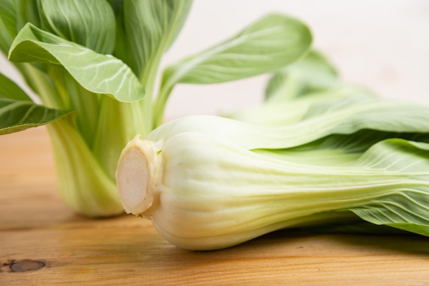 茶色の木製の背景に新鮮な緑の青梗菜またはパックチョイ白菜。