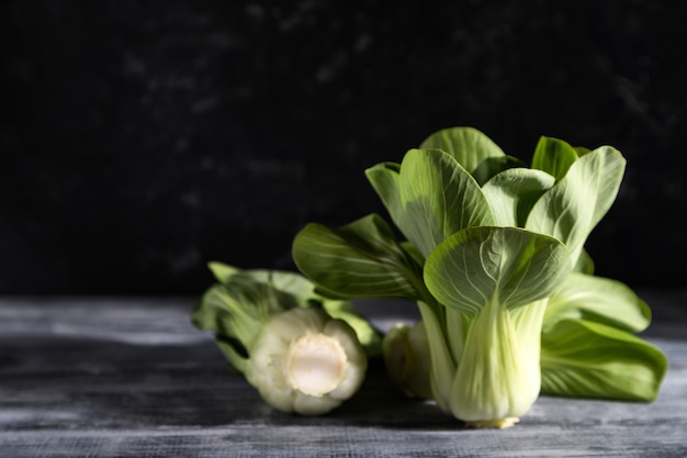 灰色の木製の背景に新鮮な緑の青梗菜またはパックチョイ白菜。