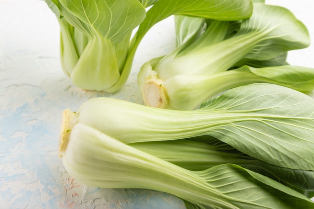 Fresh green bok choy or pac choi chinese cabbage on a white concrete background.