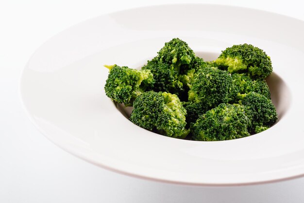 Fresh green broccoli in white circle plate isolated on white