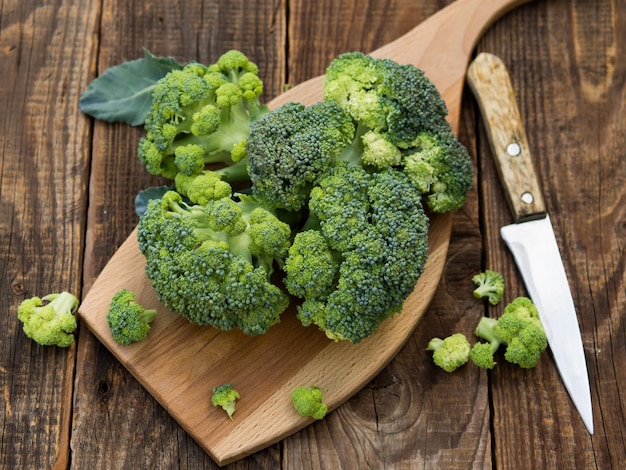 Fresh green broccoli on a wooden cutting board with a knife Broccoli cabbage leaves