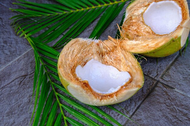 Fresh green coconut fruit cut in half and coconut leaves