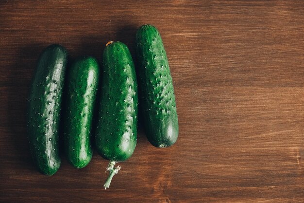 Fresh green cucumbers on a wooden table background. Top view. Copy, empty space for text