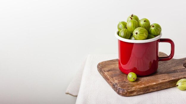 赤いエナメルのカップに新鮮な緑のグースベリーベリー.