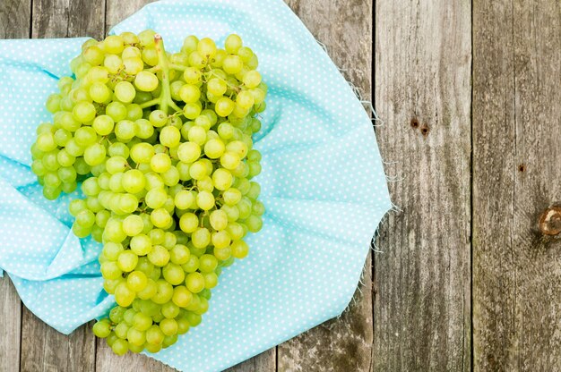 Fresh green grapes and textile napkin on old wooden background