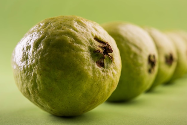 Photo fresh green guava fruit also known as amrood in hindi and peru in marathi, served in a basket as a whole or slices over colourful background. selective focus