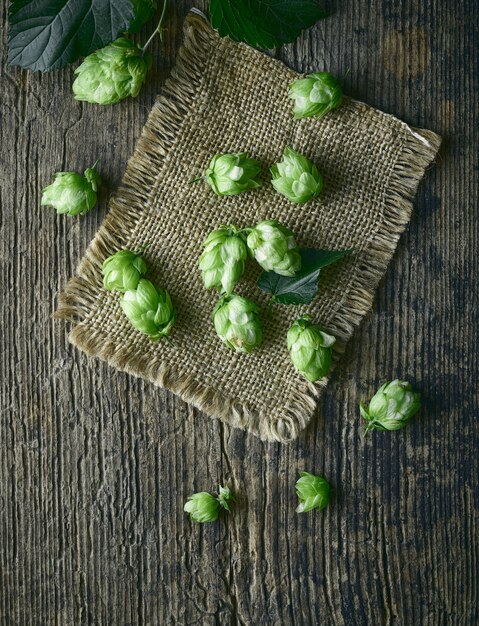 Fresh green hop plant cones on old wooden table, top view