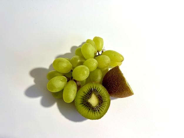 Foto kiwi verde fresco con frutta d'uva su sfondo chiaro