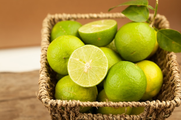 Fresh green lemon in basket on old wooden table