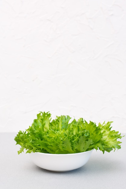 テーブルの上のボウルに新鮮な緑のレタスの葉。健康的な食事。スペースをコピーします。垂直方向のビュー