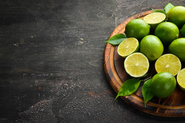 Fresh green limes with leaves Citrus fruits On a black stone background Top view Free space for your text