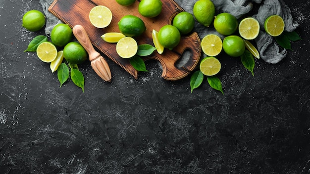 Fresh green limes with leaves Citrus fruits On a black stone background Top view Free space for your text