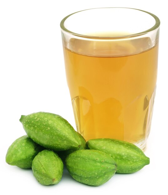 Fresh green medicinal haritaki fruits with extract in a glass