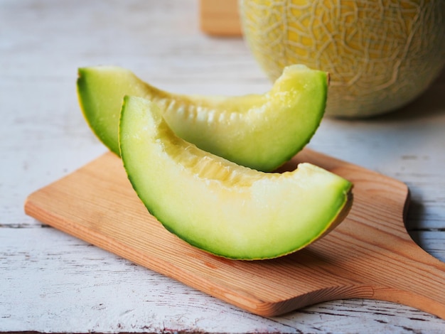 Fresh green melon fruit chopped on wooden chopping board for\
healthy eating concept