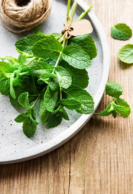 Foglie di menta verde fresca nel piatto sulla vecchia tavola di legno