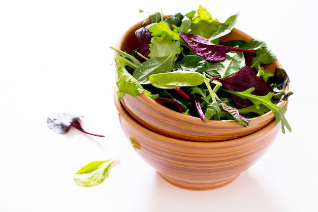 Fresh green mixed salad in a bowl on a white table