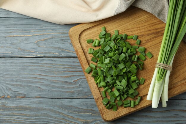 Fresh green onion on cutting board, on gray wooden table